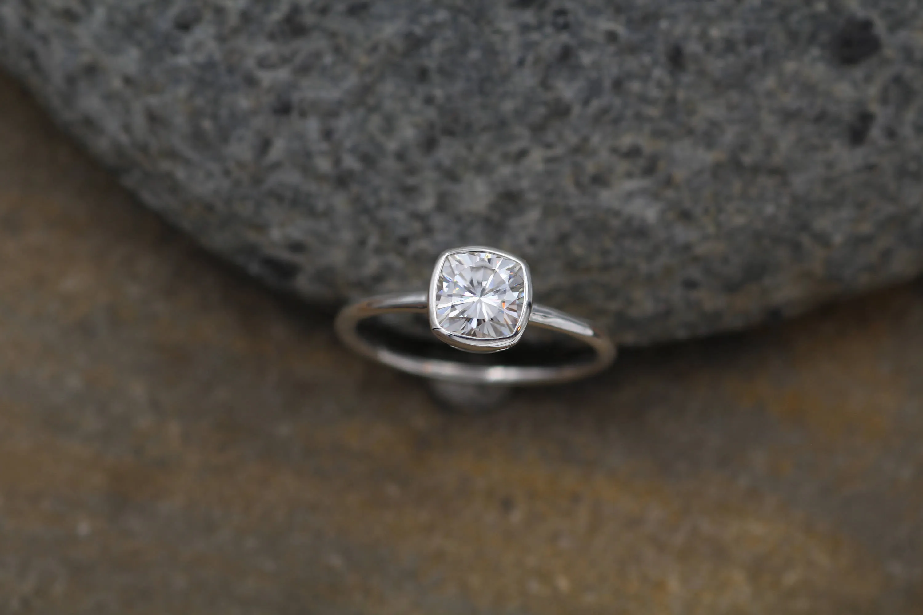 Colorless Moissanite 6x6mm Cushion Cut Bezel Solitaire Ring With A Medium/Lightweight Band