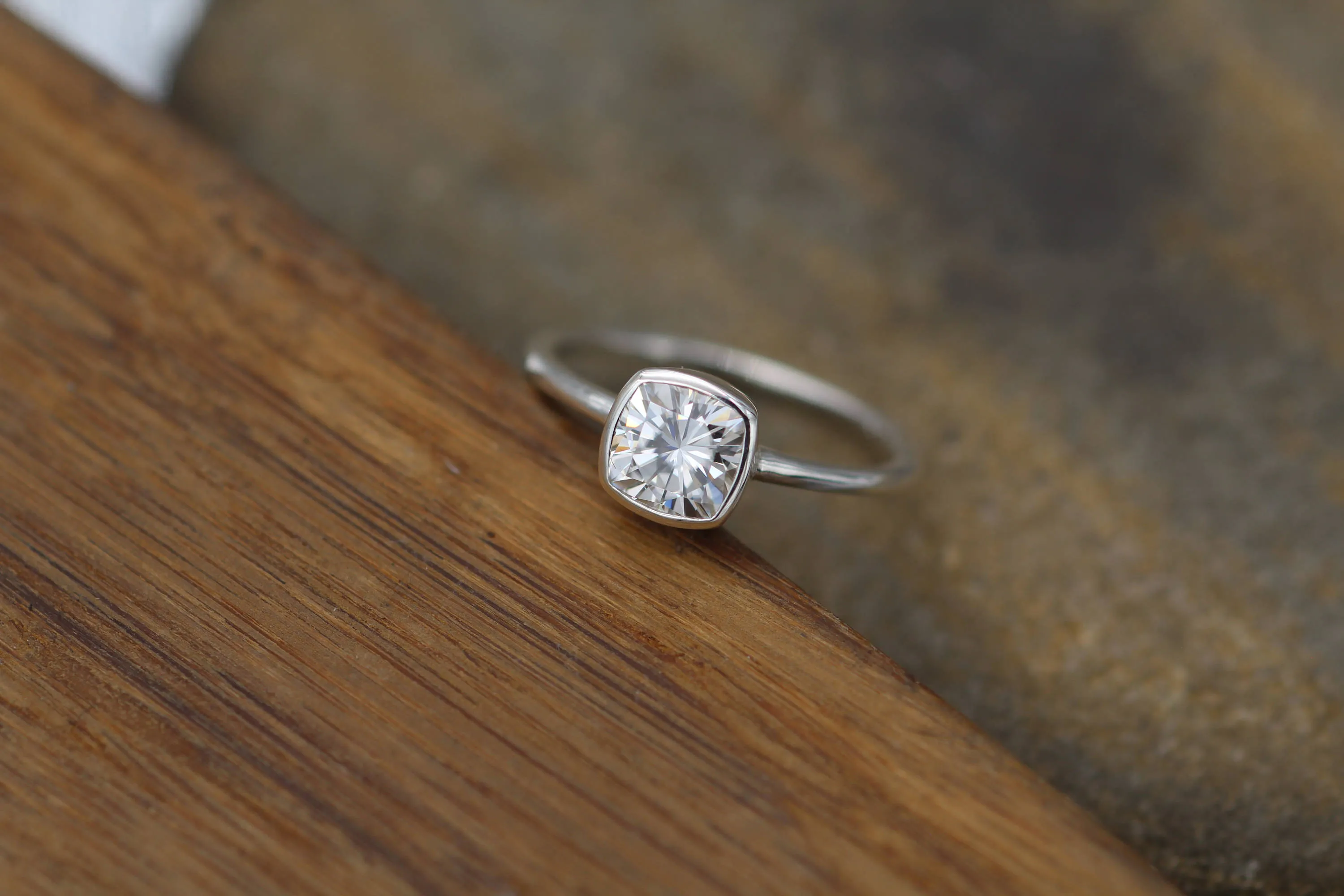 Colorless Moissanite 6x6mm Cushion Cut Bezel Solitaire Ring With A Medium/Lightweight Band