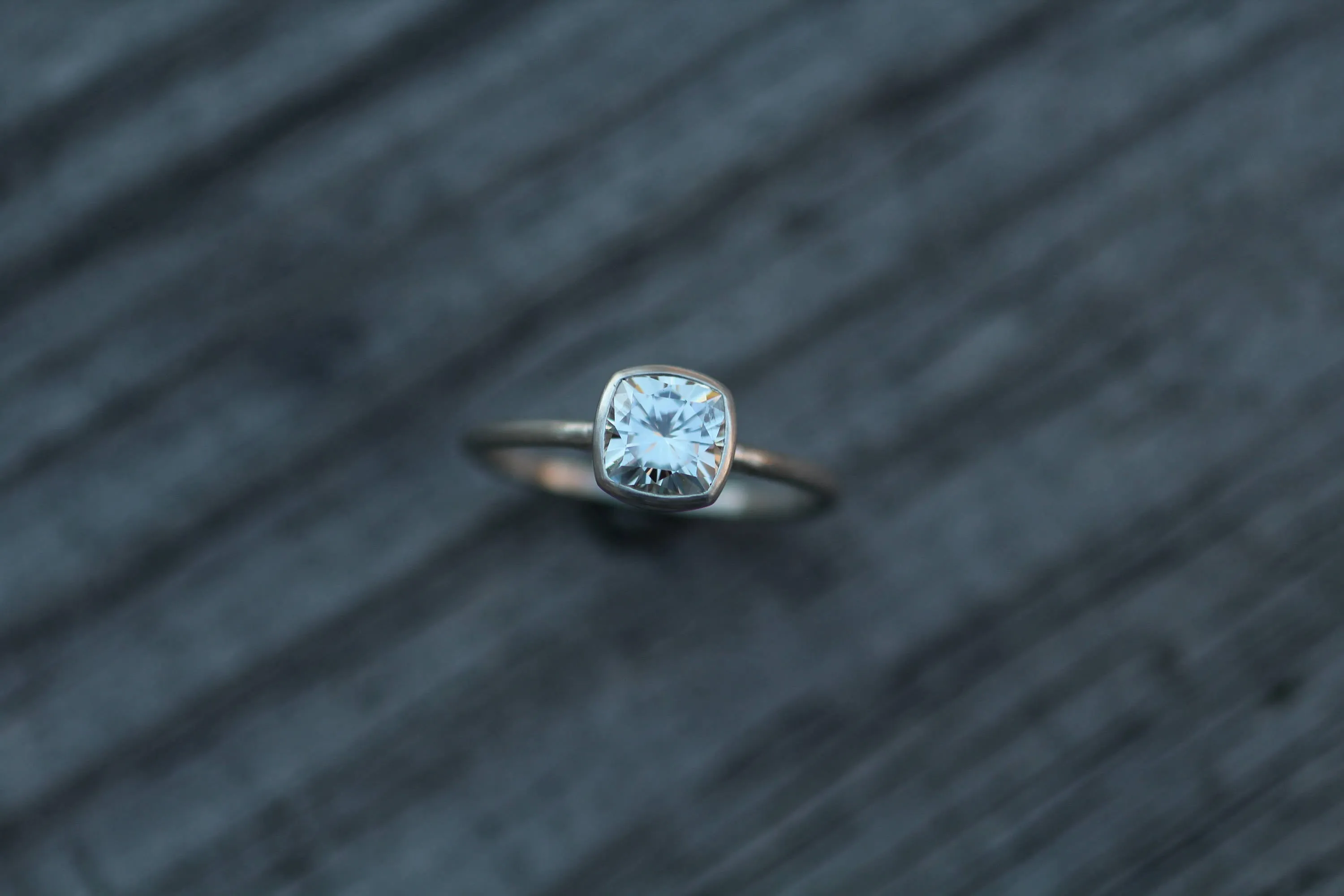Colorless Moissanite 6x6mm Cushion Cut Bezel Solitaire Ring With A Medium/Lightweight Band