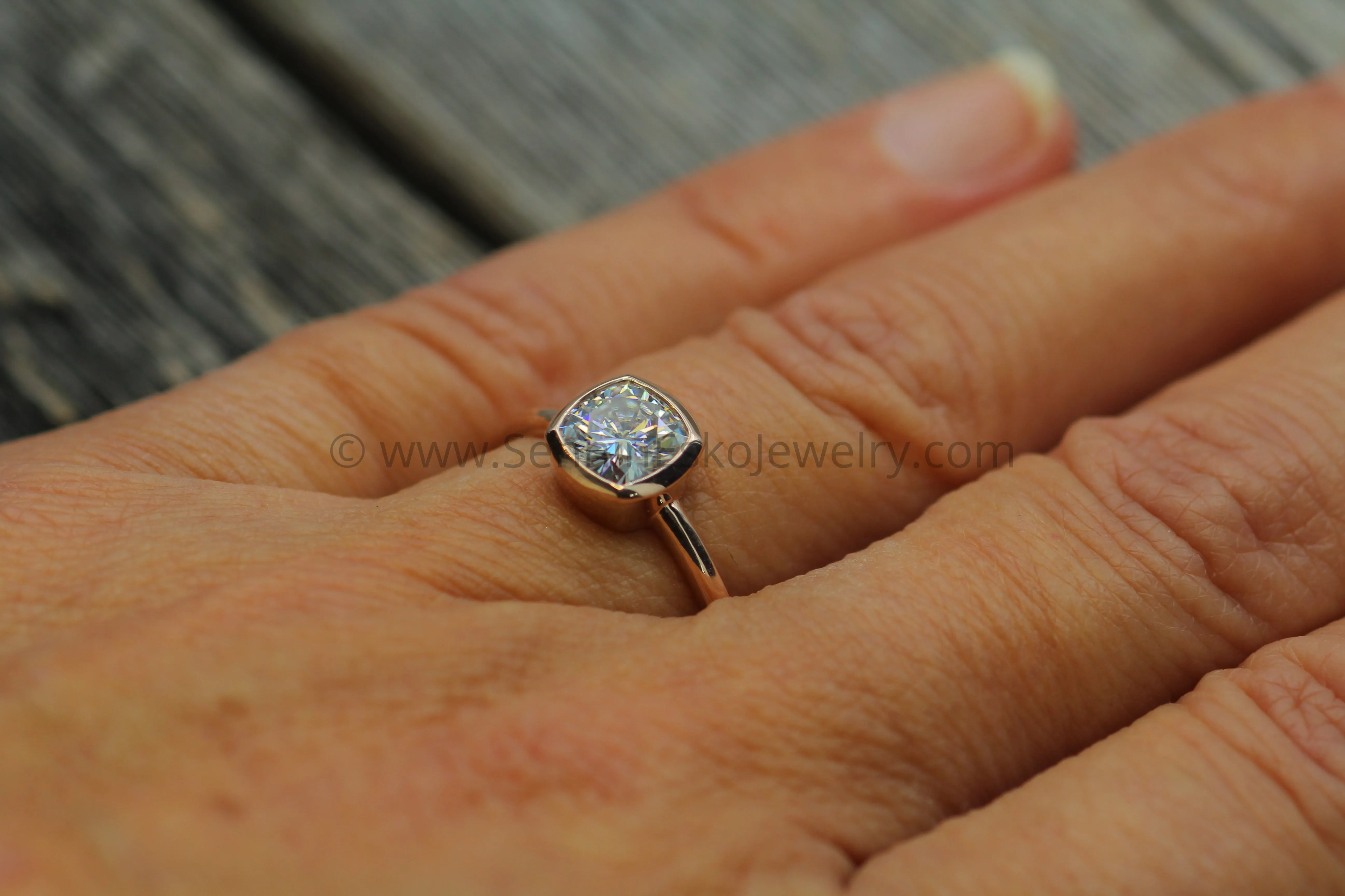Colorless Moissanite 6x6mm Cushion Cut Bezel Solitaire Ring With A Medium/Lightweight Band