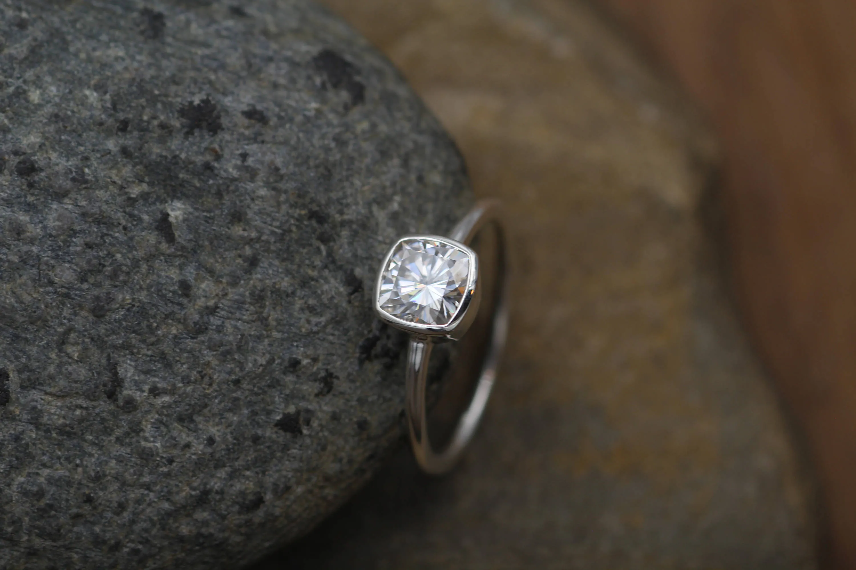Colorless Moissanite 6x6mm Cushion Cut Bezel Solitaire Ring With A Medium/Lightweight Band