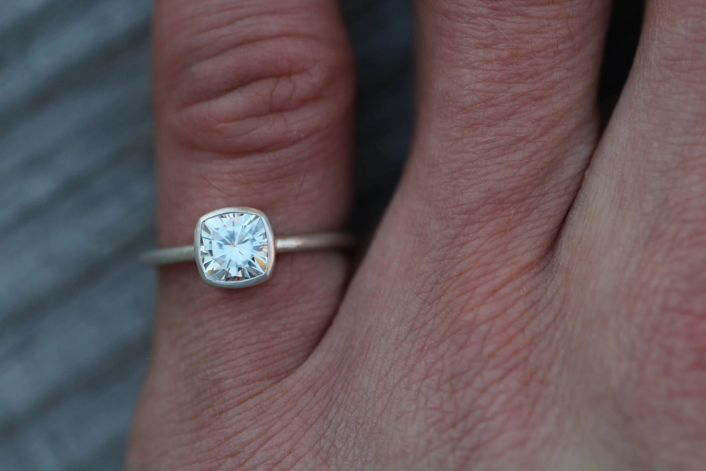 Colorless Moissanite 6x6mm Cushion Cut Bezel Solitaire Ring With A Medium/Lightweight Band