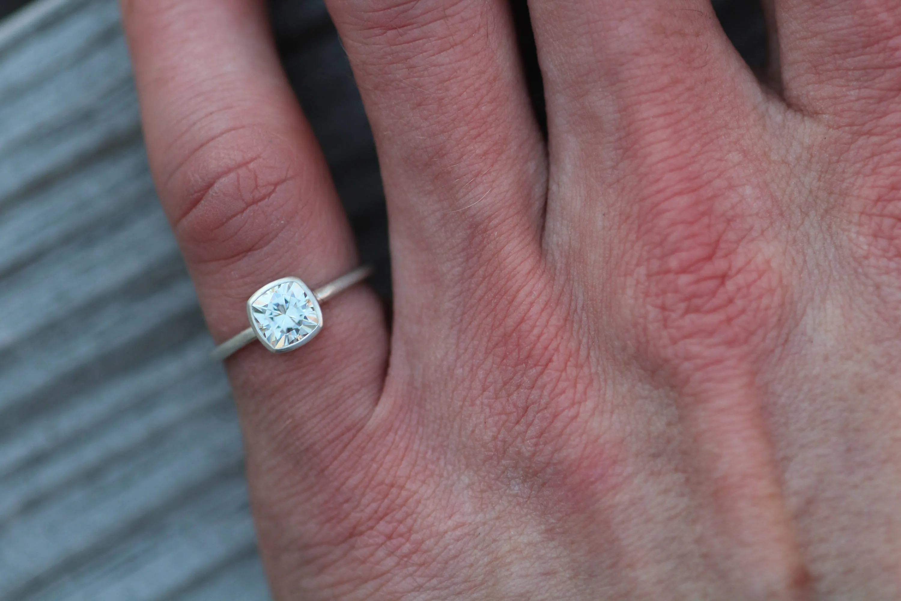 Colorless Moissanite 6x6mm Cushion Cut Bezel Solitaire Ring With A Medium/Lightweight Band
