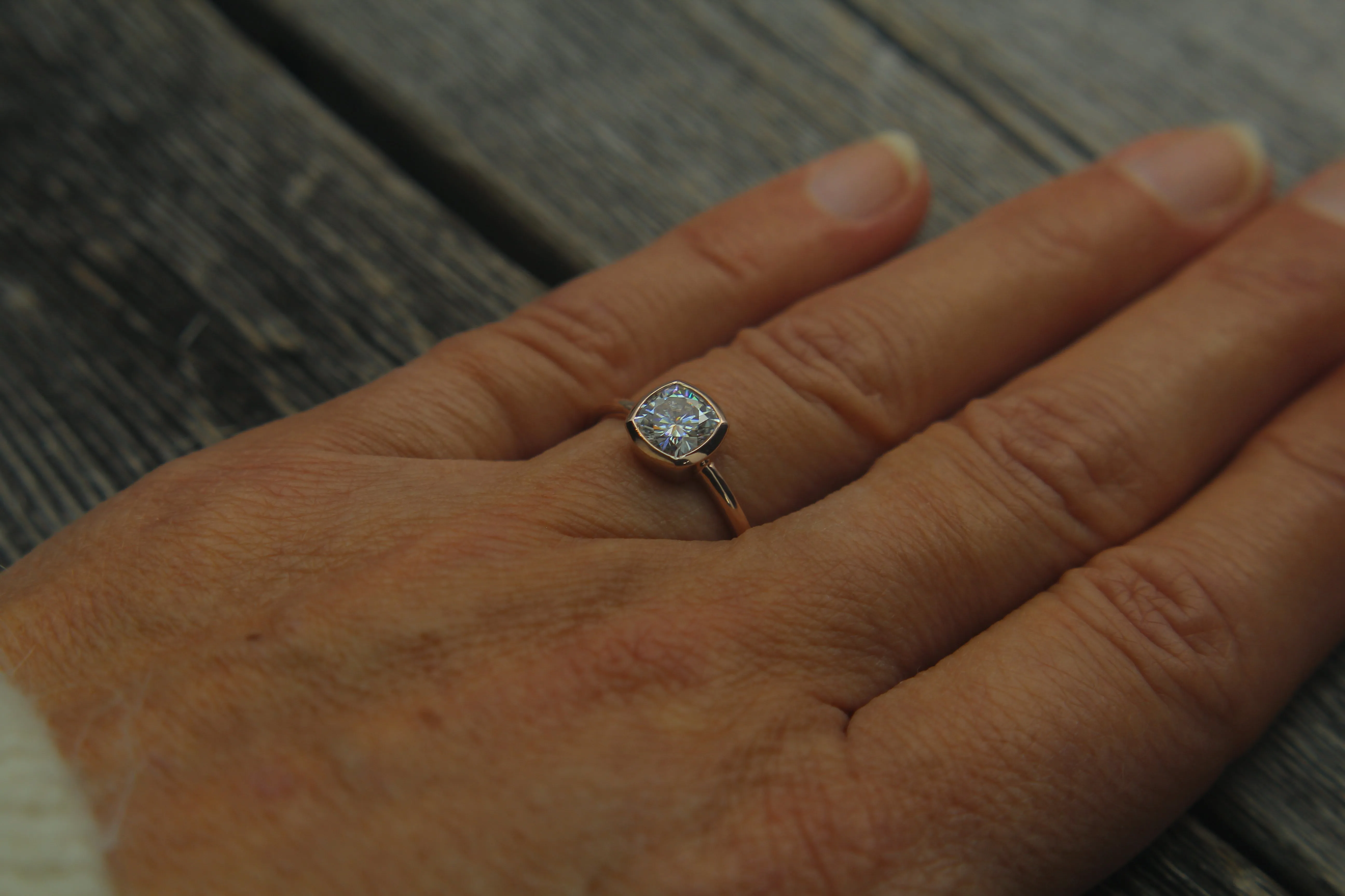 Colorless Moissanite 6x6mm Cushion Cut Bezel Solitaire Ring With A Medium/Lightweight Band